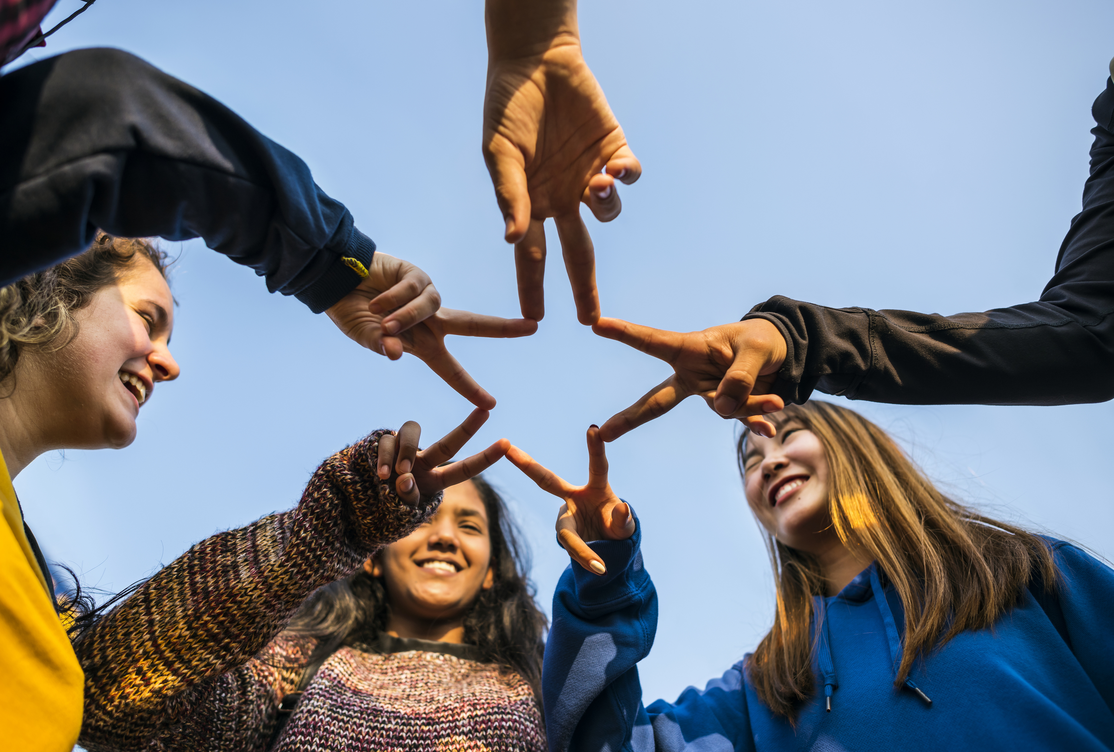 Group of friends using fingers to form the star shape teamwork and support concept